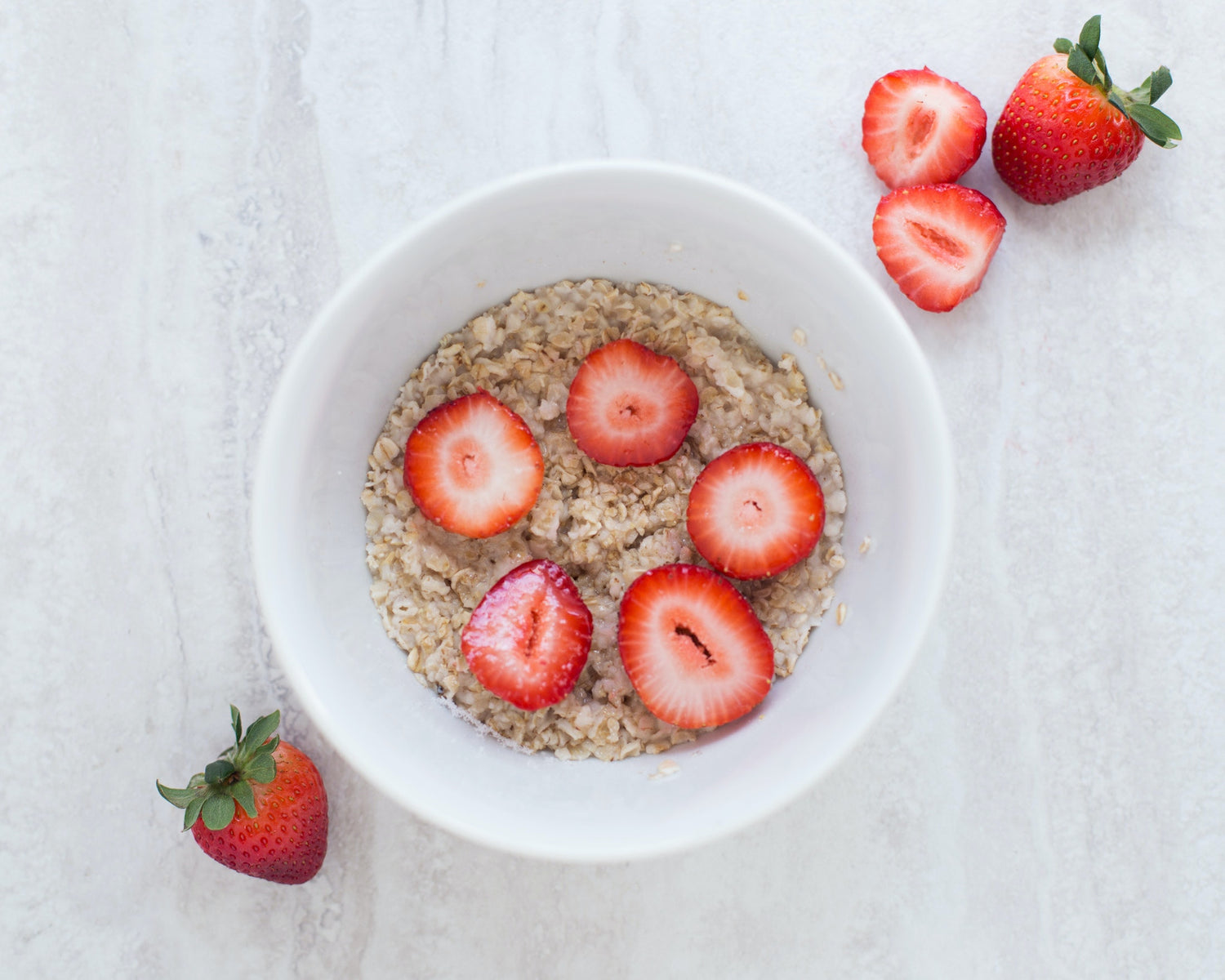 Oatmeal served with sliced strawberries on top for breakfast.